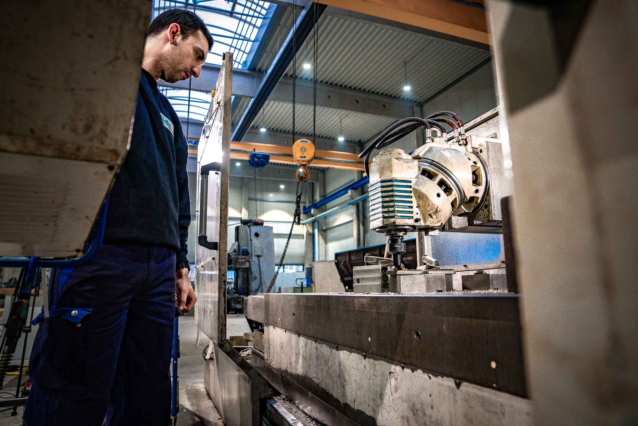 Mitarbeiter betrachtet CNC-Maschine in der Zerspanungstechnik